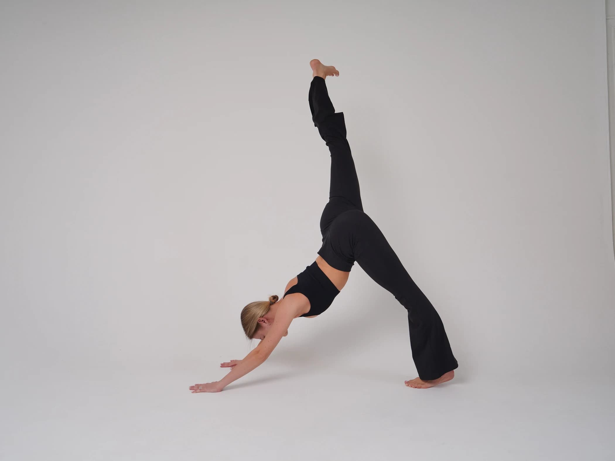 A close-up of a woman’s head, arms and hands in three-legged downward dog.