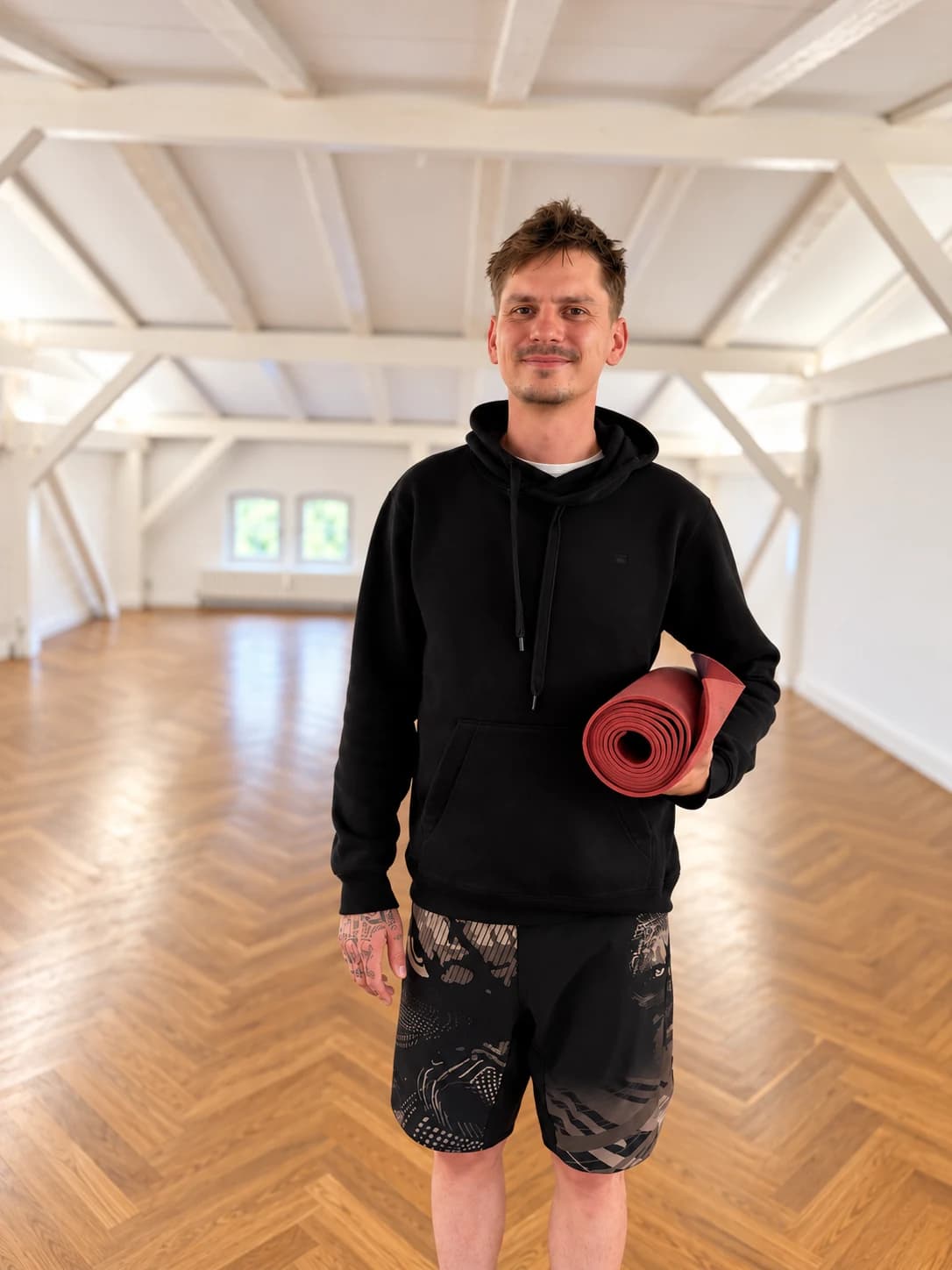 Jonas holding a yoga mat in a bright yoga studio.